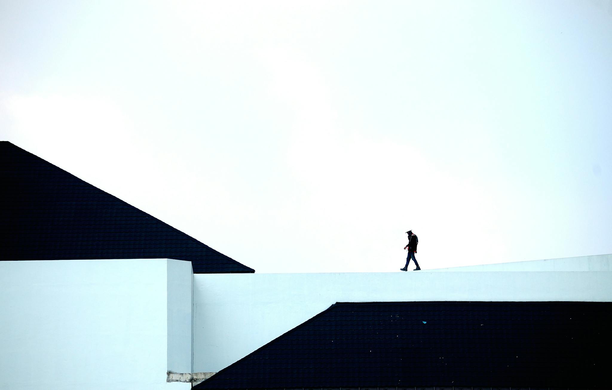 Silhouette of a person walking on a geometric architectural structure under a vast sky.
