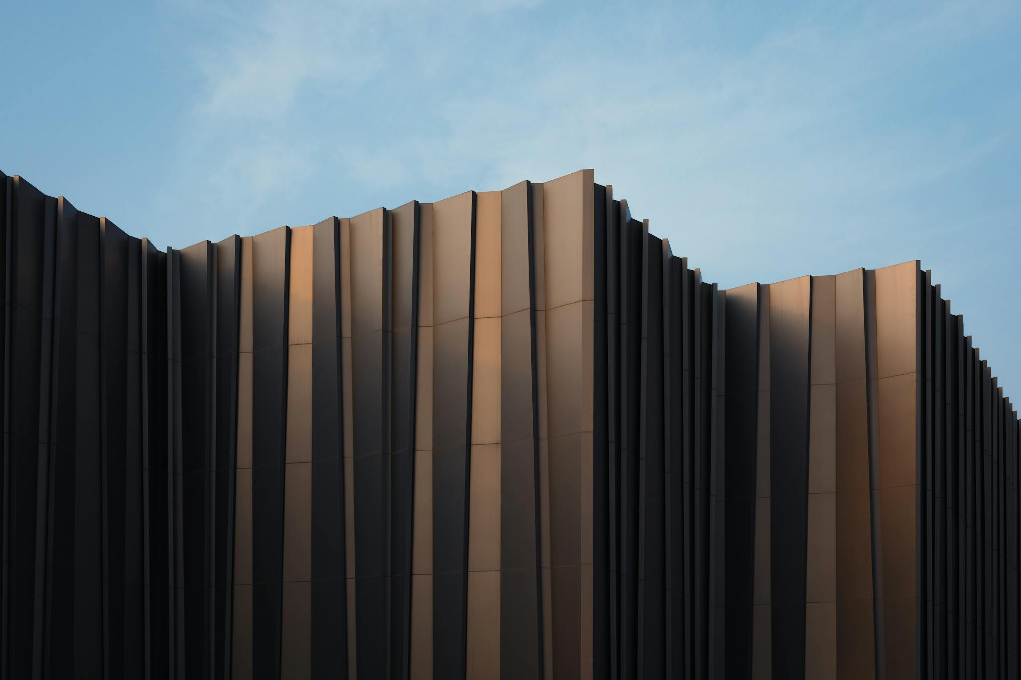 Sleek modern building facade with unique design set against a clear blue sky.